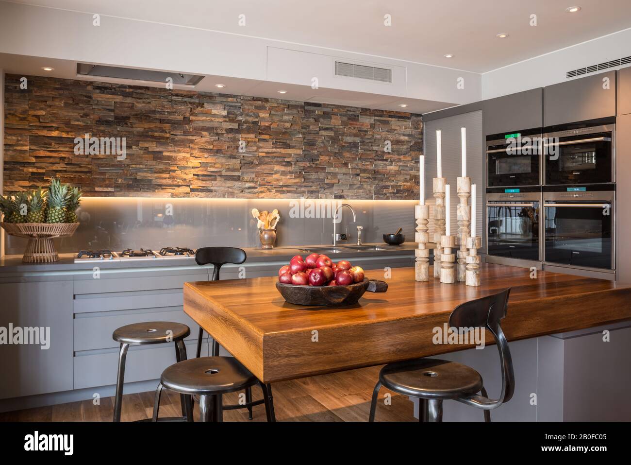 Teak breakfast bar with slate lined walls in kitchen of modern West London apartment. Stock Photo