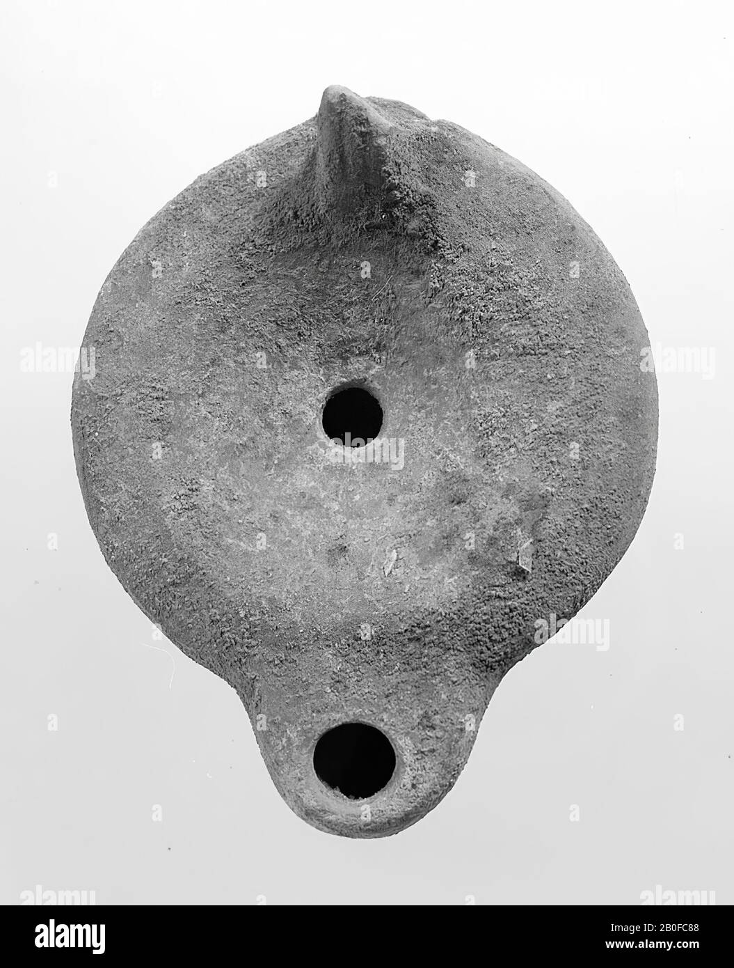 A red-nested light with a round body. The round, concave mirror is surrounded by concentric circles and undecorated with the small filling hole in the middle. The round spout has a large fire hole and a heart-shaped attack with dots on both sides. The vertically attached ear was decorated with notches, oil lamp, earthenware, terracotta, 4.3 x 9.1 x 6.9 cm, 2nd half 1st century to 1st half 3rd century AD. 50-250 AD, Tunisia Stock Photo