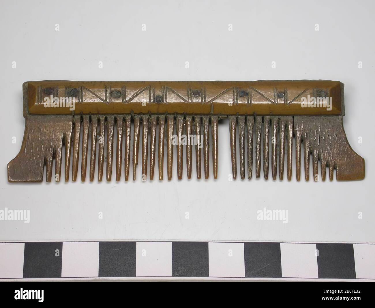 One-sided three layer comb. Type: Originally this comb was a double-sided comb. Form: The comb is now one-sided and elongated. Originally, this comb was two-sided. Saw marks on the top and bottom of the handle blades. The teeth of one of the sides have been sawn off. The teeth plates are straight filed. The shape of this comb corresponds to the shape of double-sided combs. The comb has concave short sides. This is a Frisian development. Decoration: handle sheets: lines, which form triangles and vertical lines. Both handles: identical decorated. The handle blades are narrow. Tooth plates: 4 Stock Photo