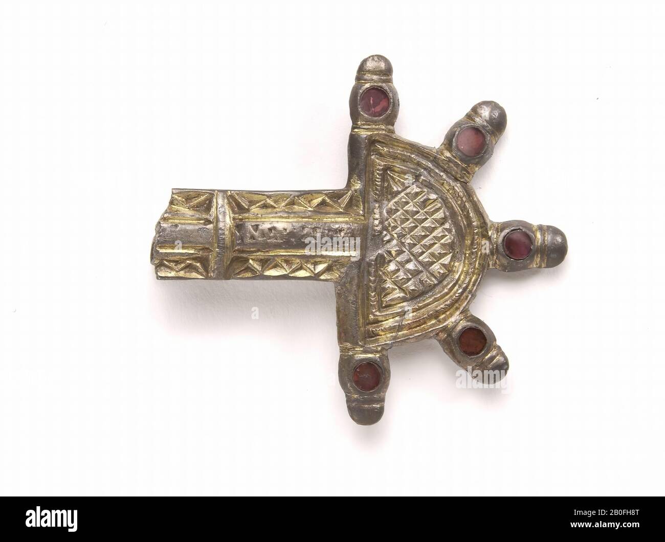 Frankish fibula. The semi-circular head plate is decorated with a diamond pattern and five buttons that are inlaid with round red glass discs. The bracket has a zigzag ornament. The lower part of the needle holder is broken., Fibula, clamp fibula, metal, silver (gold plated), almandine, 1,1 x 5,1 x 5,1 cm, 11,7 gram, vmeb 485-530, Netherlands, Gelderland, Neder -Betuwe, Echteld Stock Photo