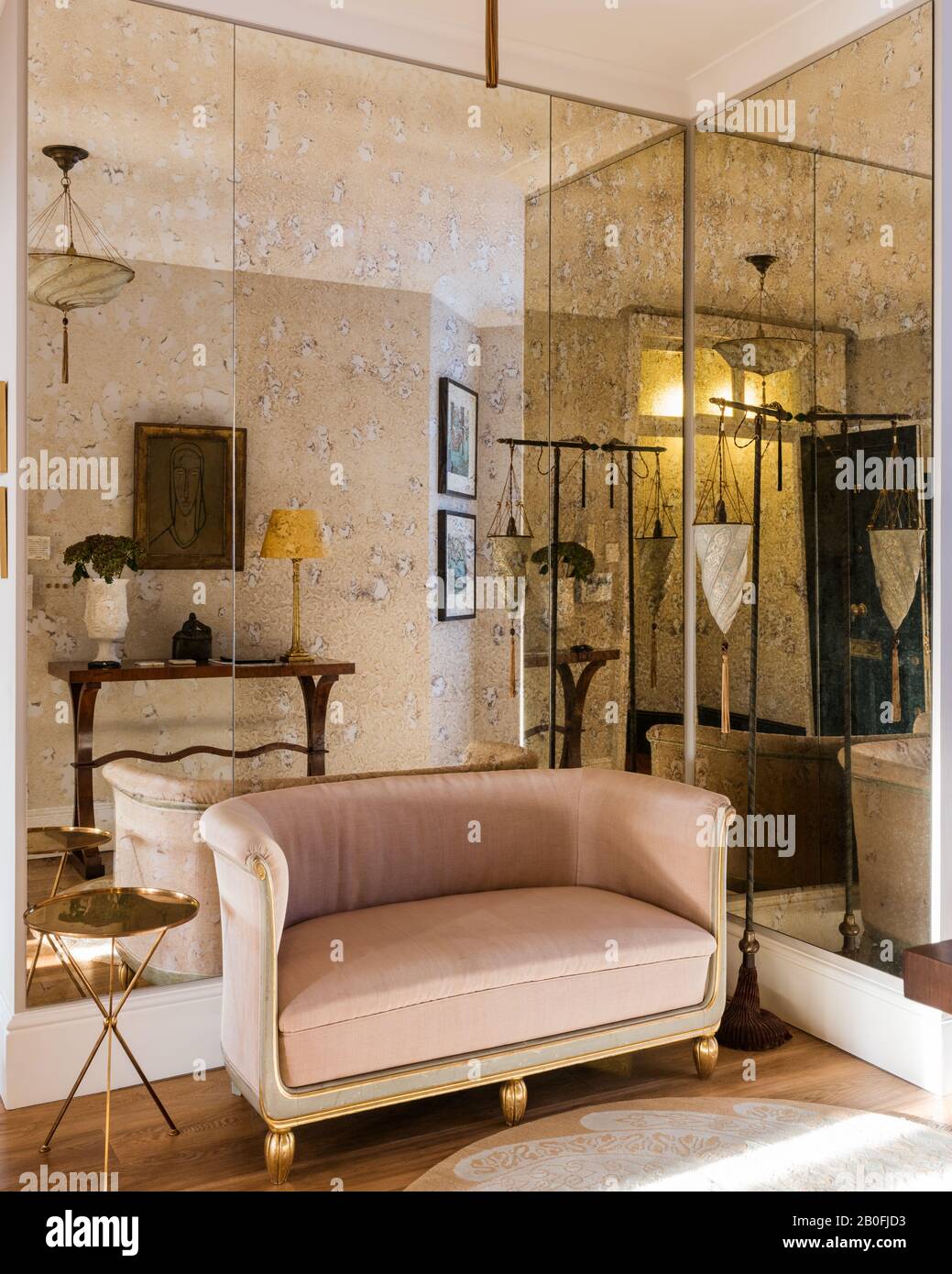 Mirrored wall with vintage French two-seater sofa upholstered in pink velvet. Stock Photo