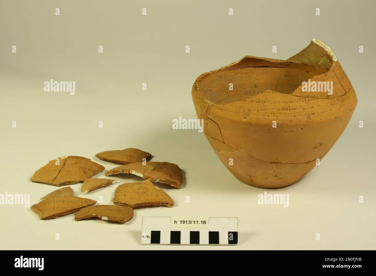 Rossy kink with a rad-temple decoration. The neck and rim are missing, old glueing and additions, of which a large number of shards have left loose at the top, hole in the bottom. Contains cremation residues., Kink pot, earthenware (Frankish), h: 16.2 cm, diam: 19.4 cm, vmeb 500-700, Netherlands, South Holland, Katwijk, Rijnsburg, cemetery Stock Photo
