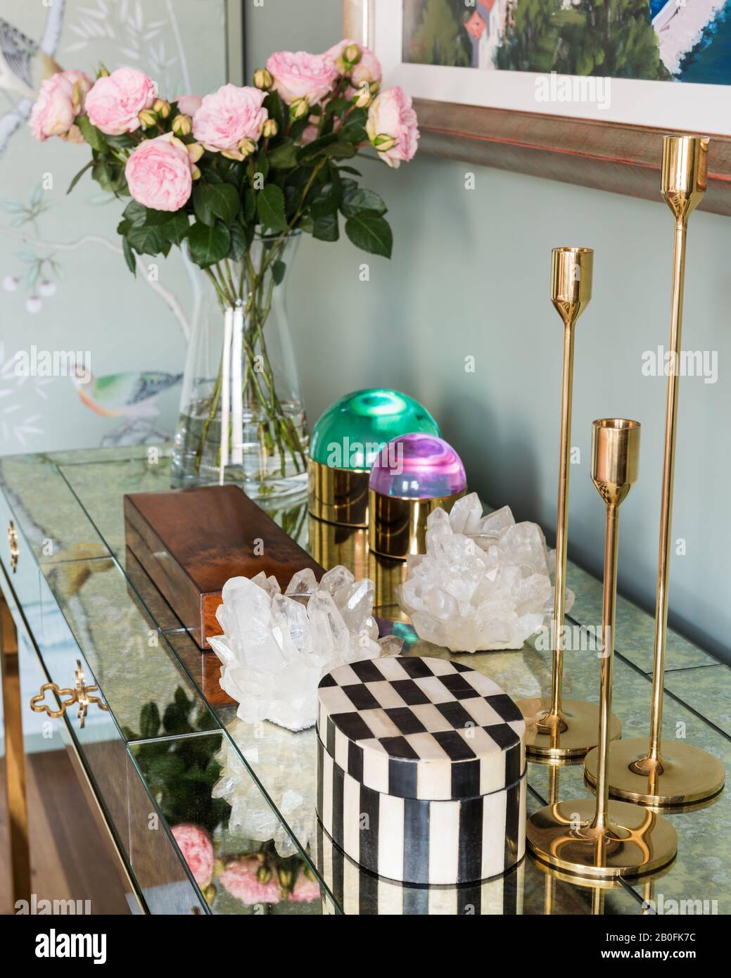 Gold candlesticks and cut flowers with jewellery boxes on cabinet Stock Photo