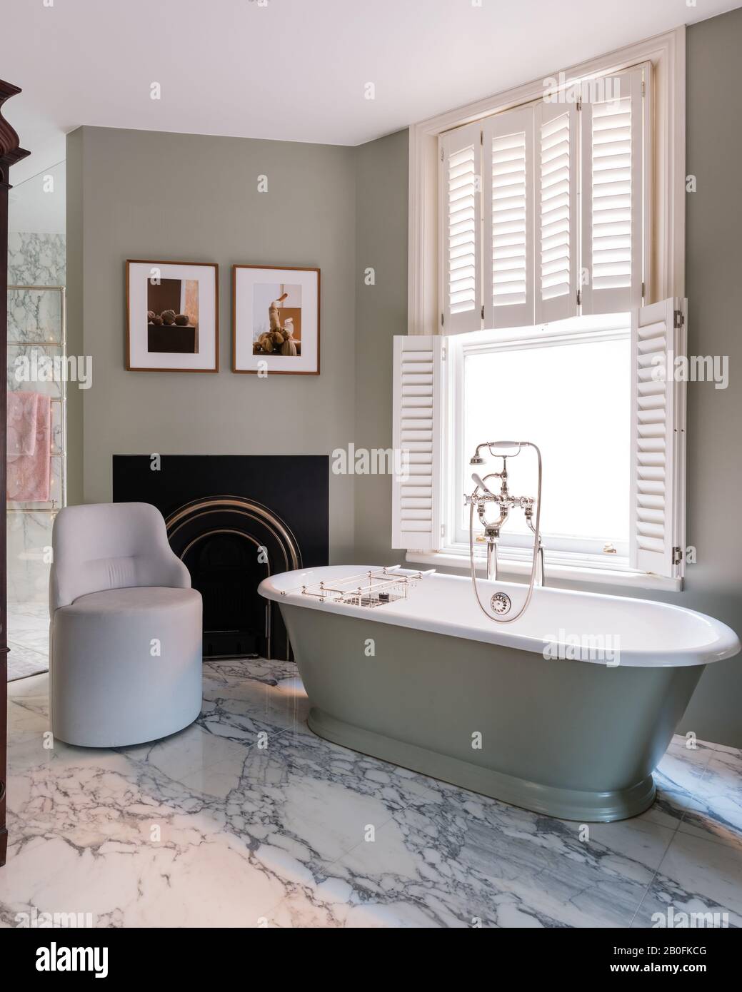 Freestanding bath at frosted glass window with plantation shutters Stock Photo