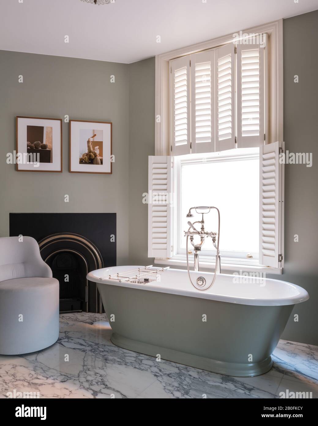 Freestanding bath at frosted glass window with plantation shutters Stock Photo