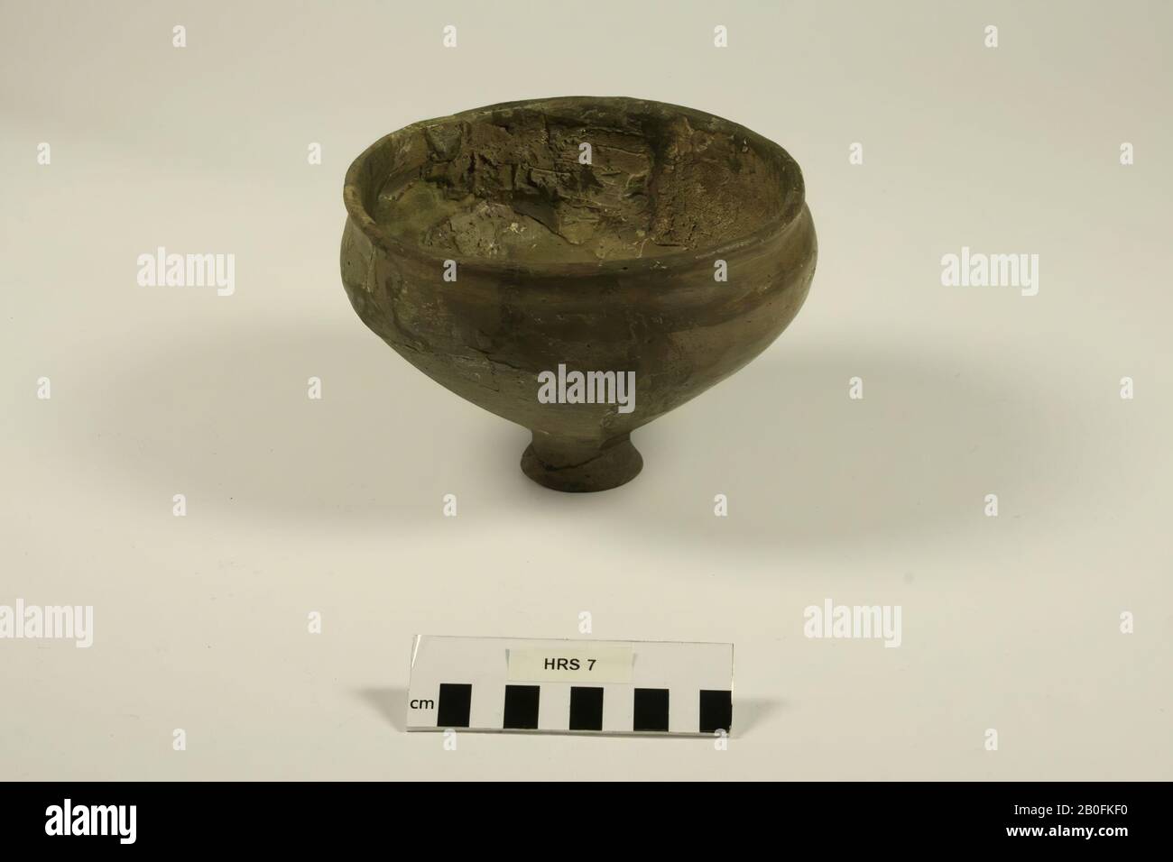 A part of a bowl of brownish gray somewhat finer mixed and baked earth, but very fragile, on the inner wall with parallel and one-centered stripes, thus certainly formed on the race. The opening is very wide, the foot is small. Various glueing and additions., Footplate, pottery (Saxon), h: 11.3 cm, diam: 17 cm, lmea 400-500, Netherlands, Drenthe, Midden-Drenthe, Hooghalen, cemetery Stock Photo
