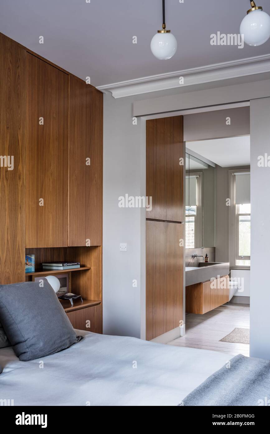 American walnut wall unit with bedside shelves with bed throw by De la Cuona and Array ceiling light by CTO. Stock Photo