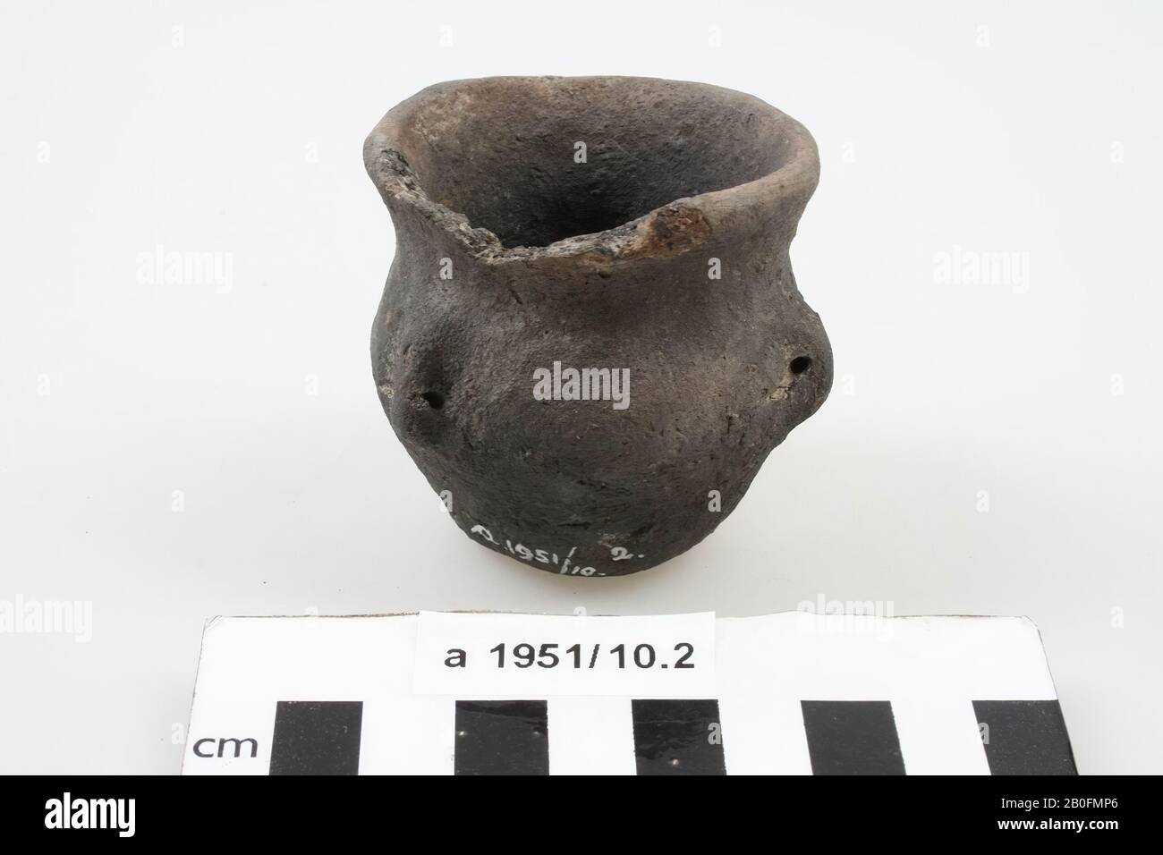Pot with three ears of dull, black smothered, hand-formed, earthenware. The rim is damaged., Pot, earthenware (hand molded), h: 5.6 cm, diam: 5.7 cm, br (incl. Ears): 6.3 cm, roman, Netherlands, Friesland, Ferwerderadiel, Janum Stock Photo