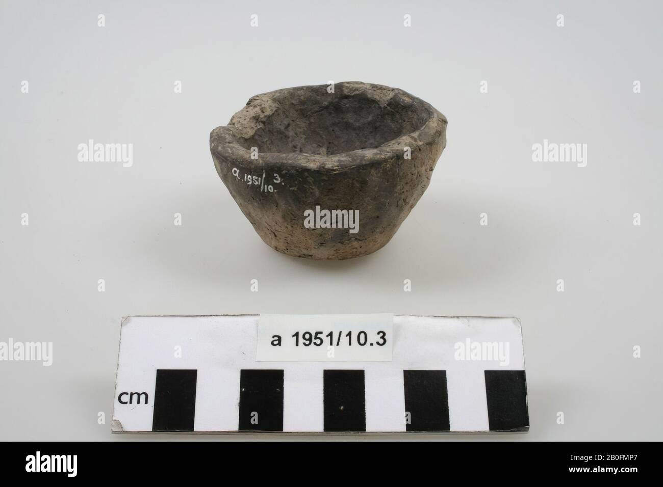 Inverted-frustoconical cup of dark and light gray mottled, hand-formed earthenware. Piece of the rim is missing., Cup, earthenware (hand molded), h: 4,4 cm, diam: 7,5 cm, roman, Netherlands, Friesland, Ferwerderadiel, Janum Stock Photo