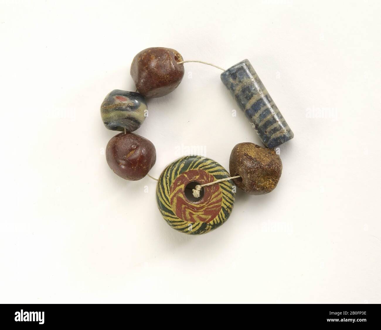 1: 1 bead of translucent blue glass with white spiral. H: 2.5 D: 0.9 2: 3 cubic amber beads. H: 1,3 D: 1,5 3: 1 cylindrical bead of rolled bands millefioriglas. H: 1.3 D: 2.2 4: 1 round millefiori beads. H: (supplement), bracelet, beads, glass, organic, amber, height: 2.5 cm, vmeb 400-600, Netherlands, Utrecht, Rhenen, Rhenen, grave 601 Stock Photo