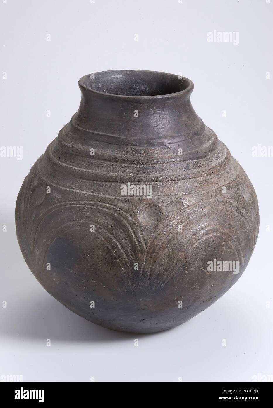 Large pot of black-brown earth on the belly with five semi-arcuate, upcoming decorations and decorated with three emerging ribs on the neck. Part of the neck is missing. Restored. Some long, vertical cracks, urn, pottery (Saxon), h: 22.4 cm, diam: 21.8 cm, lmea 400-500 AD, Netherlands, Drenthe, Tynaarlo, Midlaren Stock Photo