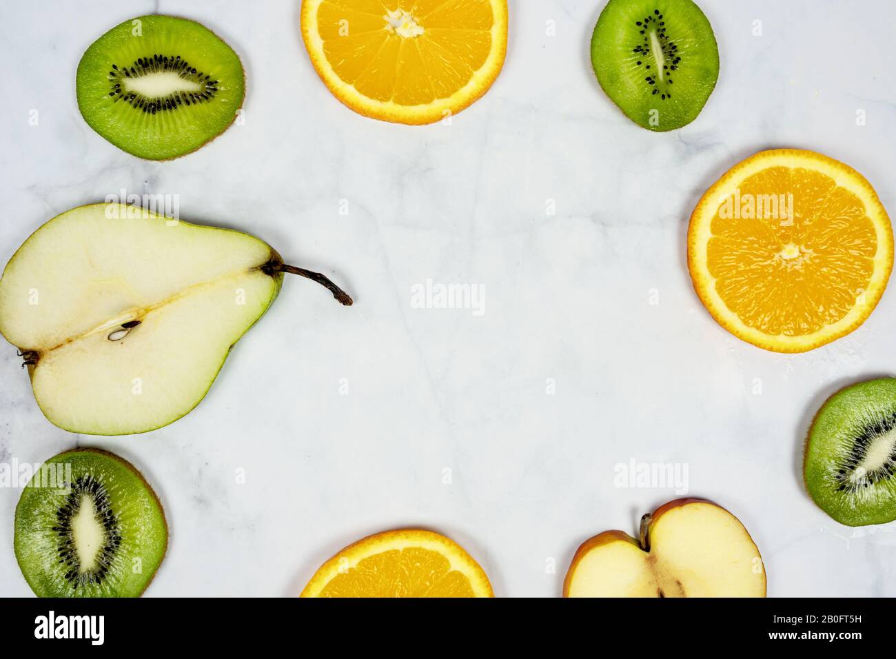 sliced fruits pear kiwi orange apple frame with minimalist marble background Stock Photo
