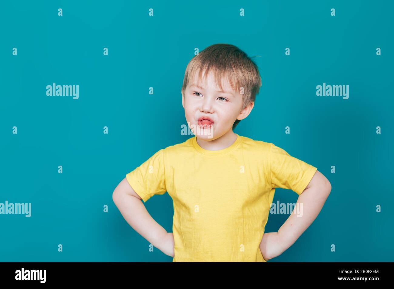 little boy shows his tongue in yellow t-shirt Stock Photo