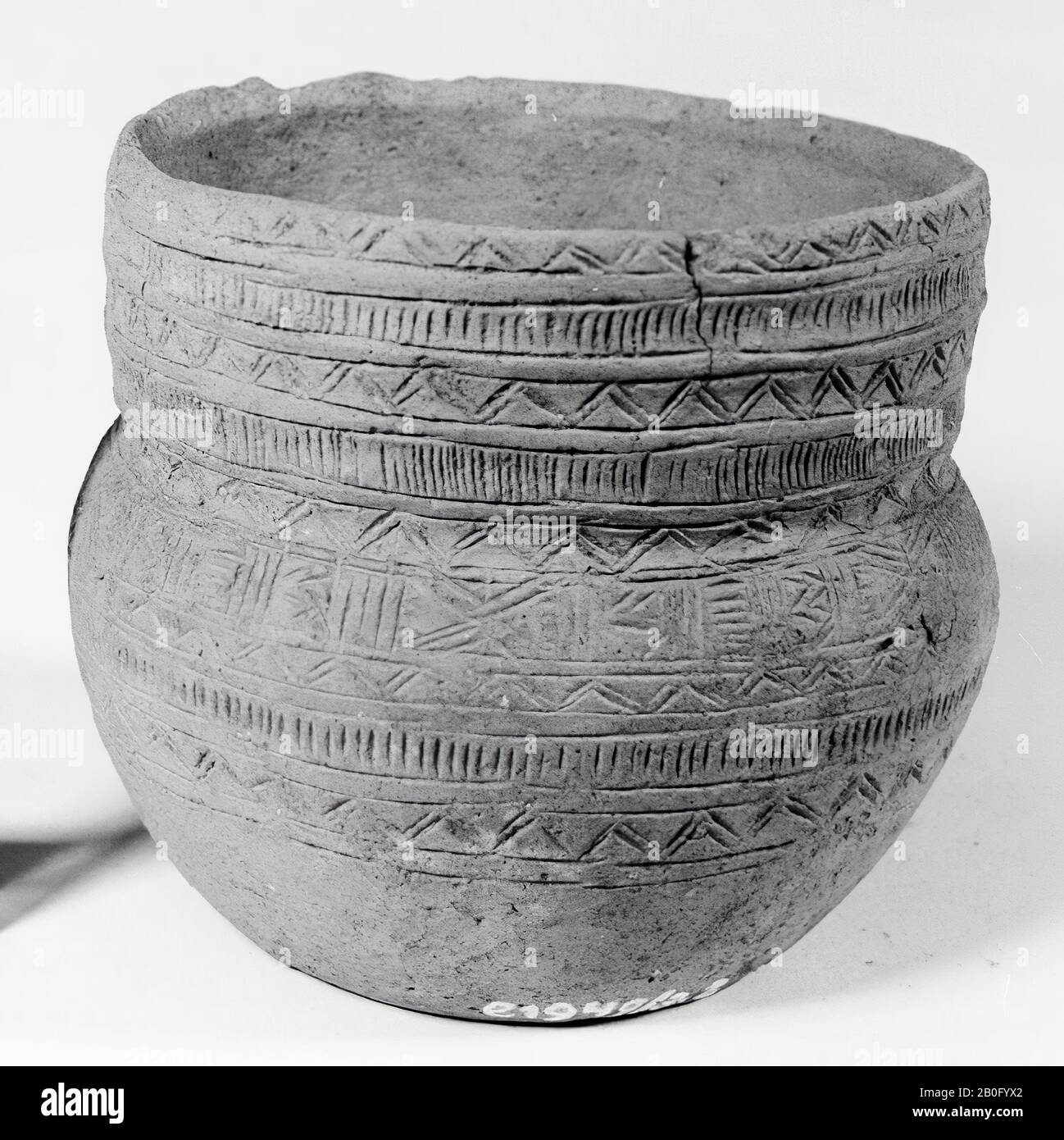 Small beaker with sun trim, the rim is decorated with three zones of horizontally arranged bands, consisting of a double zigzag line, between which two bands with vertically arranged line pieces. Below is a broad list of horizontal and crossed lines and zigzag line figures. Then two zones of horizontal bands follow with zigzag line decoration, between which there is again a band of vertically arranged line pieces. Yellow-brown pottery. 2 Cracks in the rim., Cup, earthenware, h: 11.1 cm, diam: 13 cm, prehistorie -2300 Stock Photo