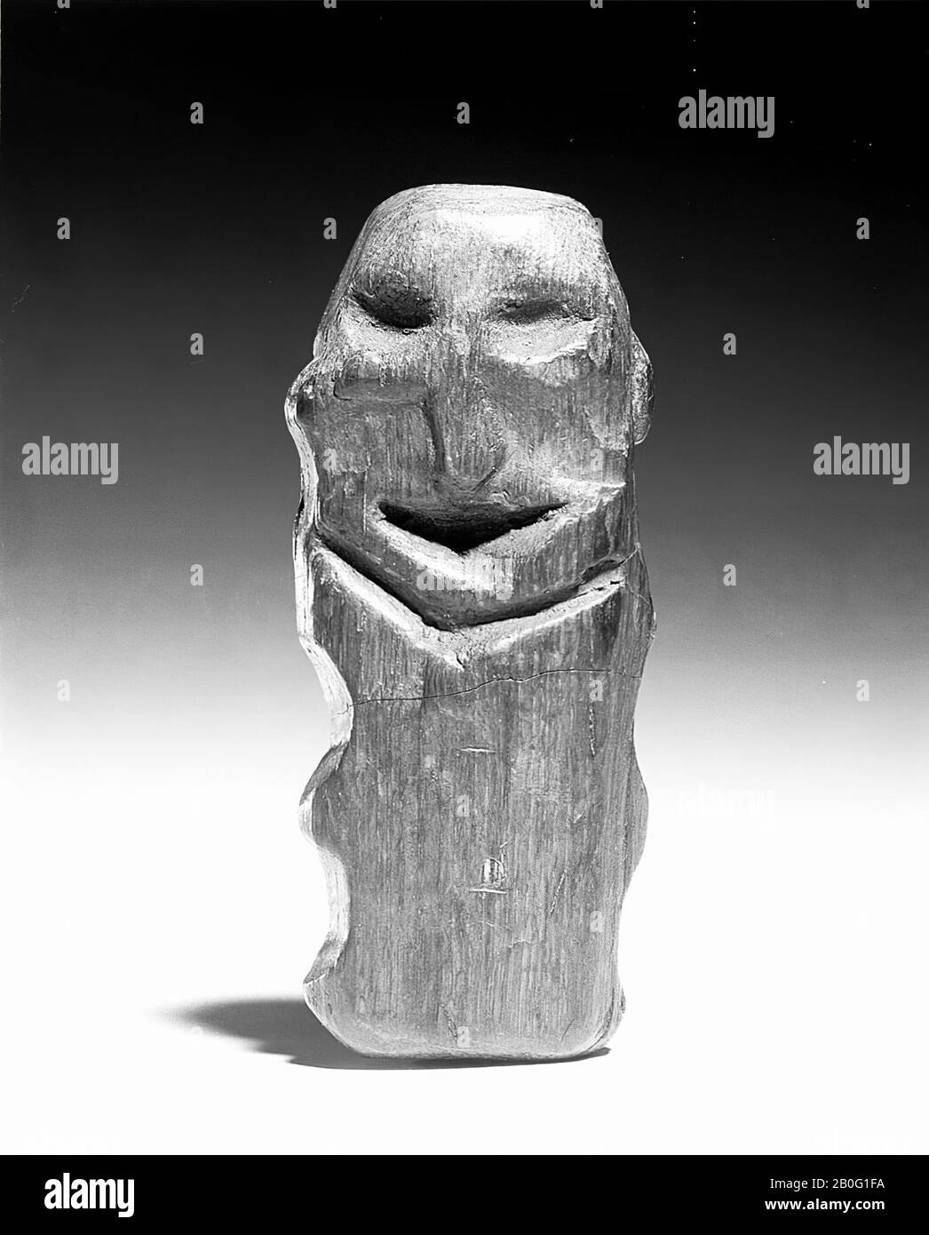 wooden sculpture. A big head on a small body, to which small protrusions must represent the limbs. Eyes and mouth are carved, as well as the separation between head and trunk. Because the wood has been cut away from the cheeks, the nose protrudes slightly. The ears are indicated on the sides as nodules. The backside is modified, idol, organic, wood, 12.4 x 5.1 x 3.1 cm, prehistory 5400-5300 BC, Netherlands, North Brabant, Moerdijk, Willemstad, Volkerak Stock Photo