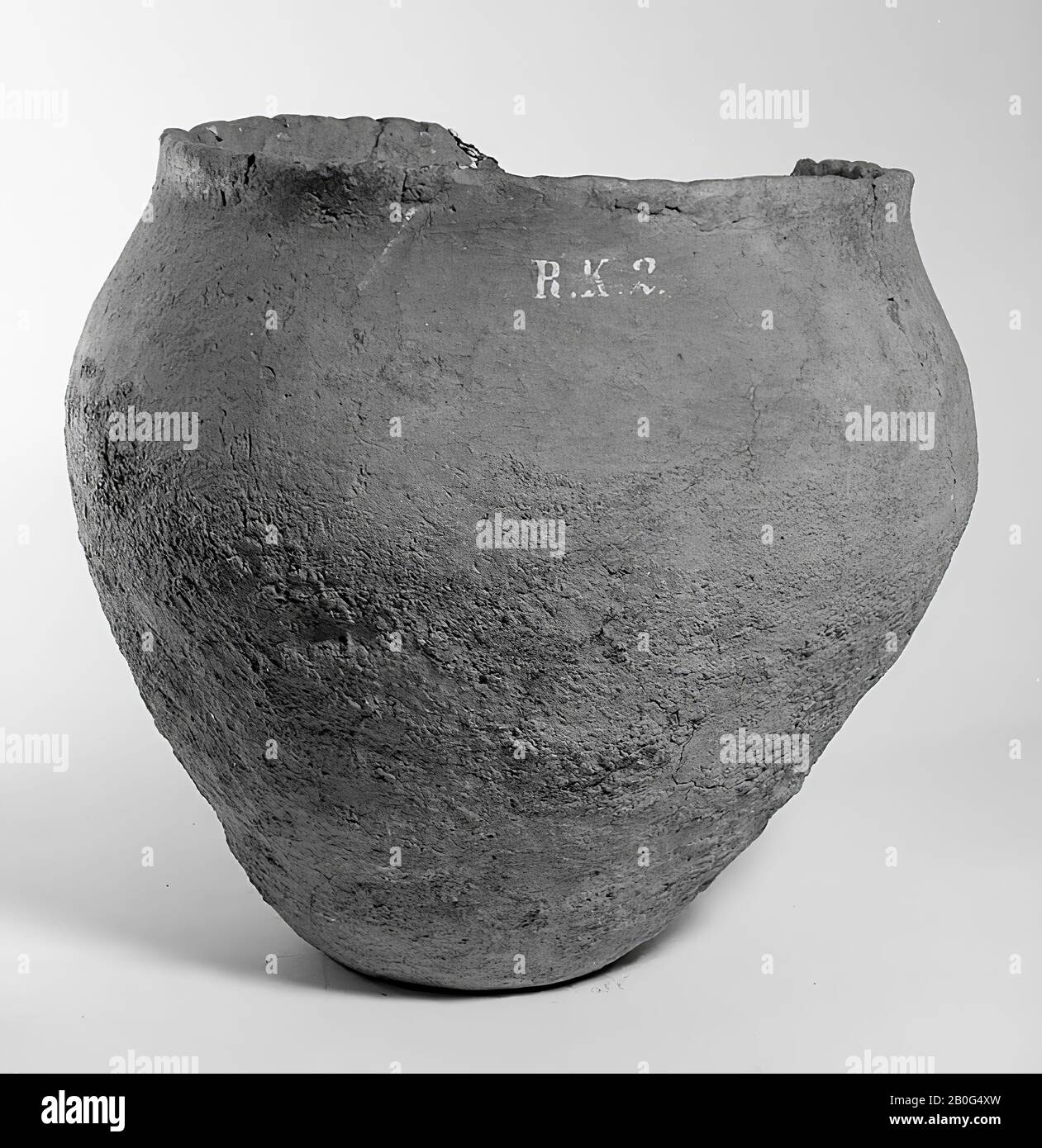 Pot of brown, roughly processed earth mixed with gravel of cobblestones hand-crafted, but baked pretty hard. The edge from above decorated with small dimples, damaged on one side. Has been filled with burned bones. Old bondings and additions, moving cracks., Urn, earthenware, h: 25.7 cm, diam: 27.5 cm, prehistory -800 Stock Photo