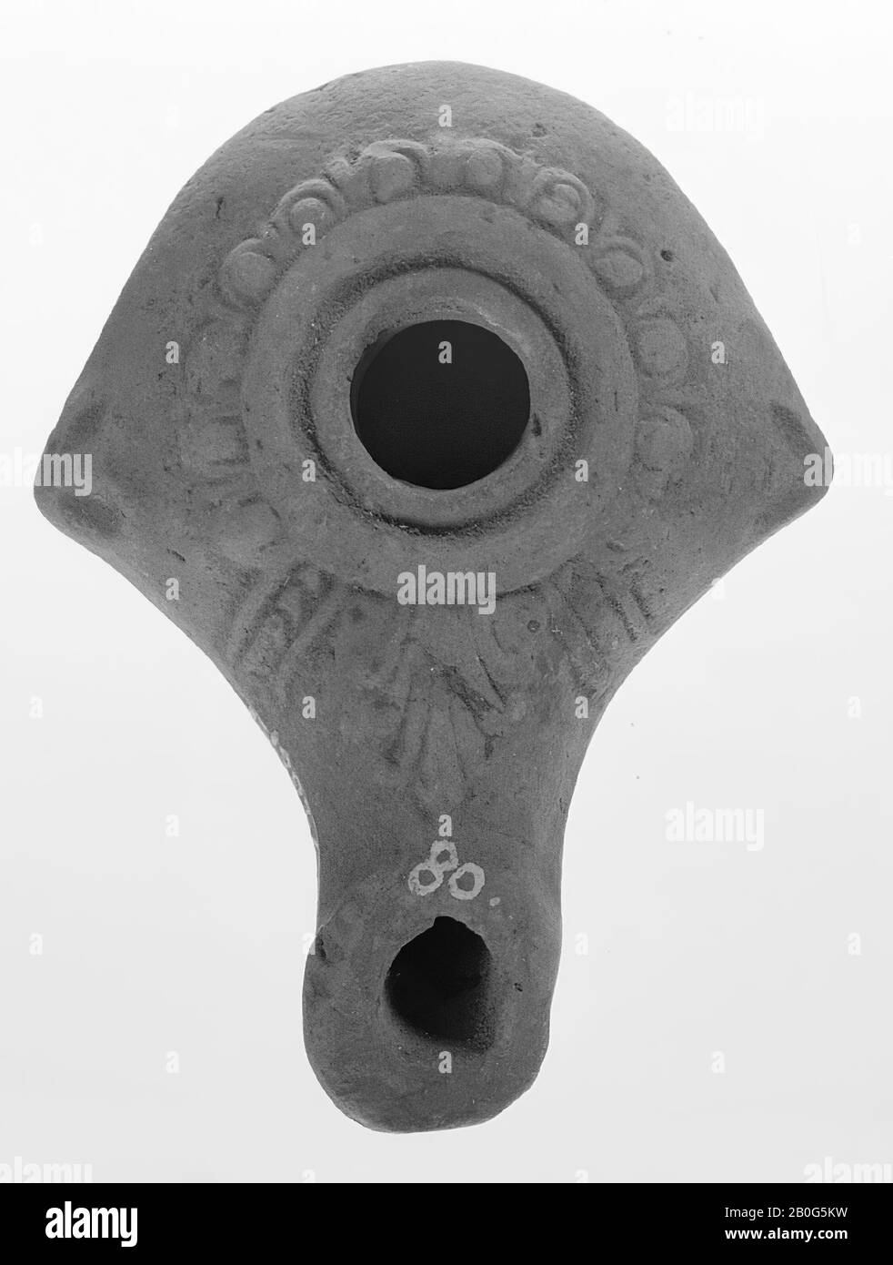 An oil lamp of light red earthenware with a round body on a layer of round base and a small filling hole surrounded by two relief rings. The shoulder is decorated with staff ornaments and at the beginning of the spout there are two vertical bands. The long rounded spout is decorated with a palmet. On both sides of the shoulder are two short pointed handles., Oil lamp, earthenware, terracotta, 2.9 x 5.8 x 7.8 cm, 2nd and 1st century BC. 0-1, Palestine Stock Photo
