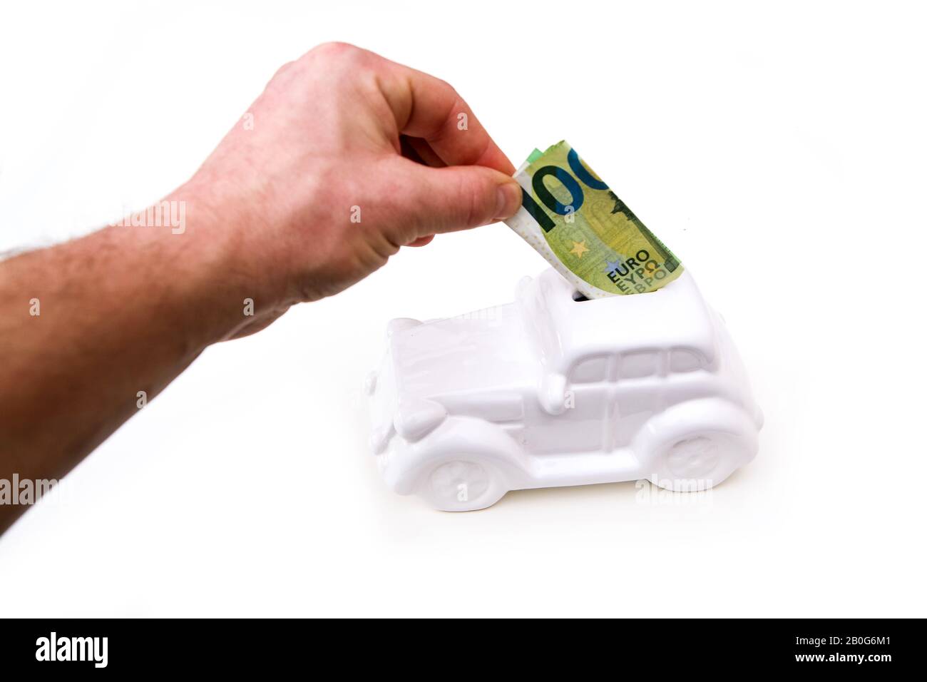 The hand is puting a banknote into the ceramic car shaped money box. It can be symbol for costs for car´s repairs, investment, savings or insurance. Stock Photo