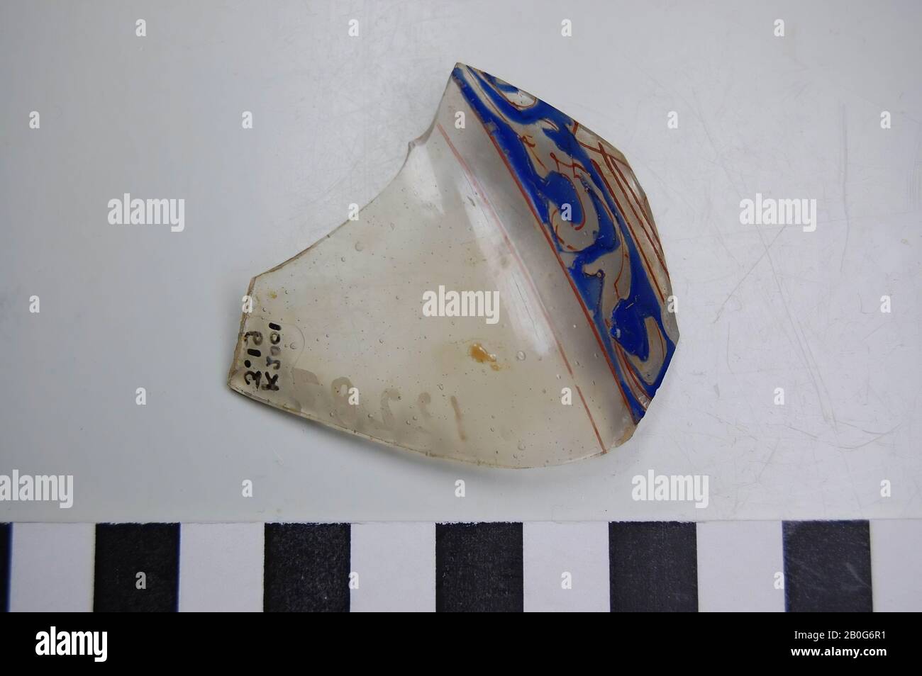 Glass shard with blue, red and gold decoration. Transparent glass with air bubbles. Old inventory number: 12287., shard, glass, 5.5 x 4.8 cm, Roman 50-100, unknown Stock Photo
