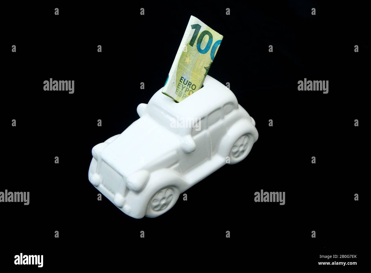 The ceramic car shaped money box with a banknote inside. It can be symbol for costs for car´s repairs, investment, savings or insurance. Stock Photo