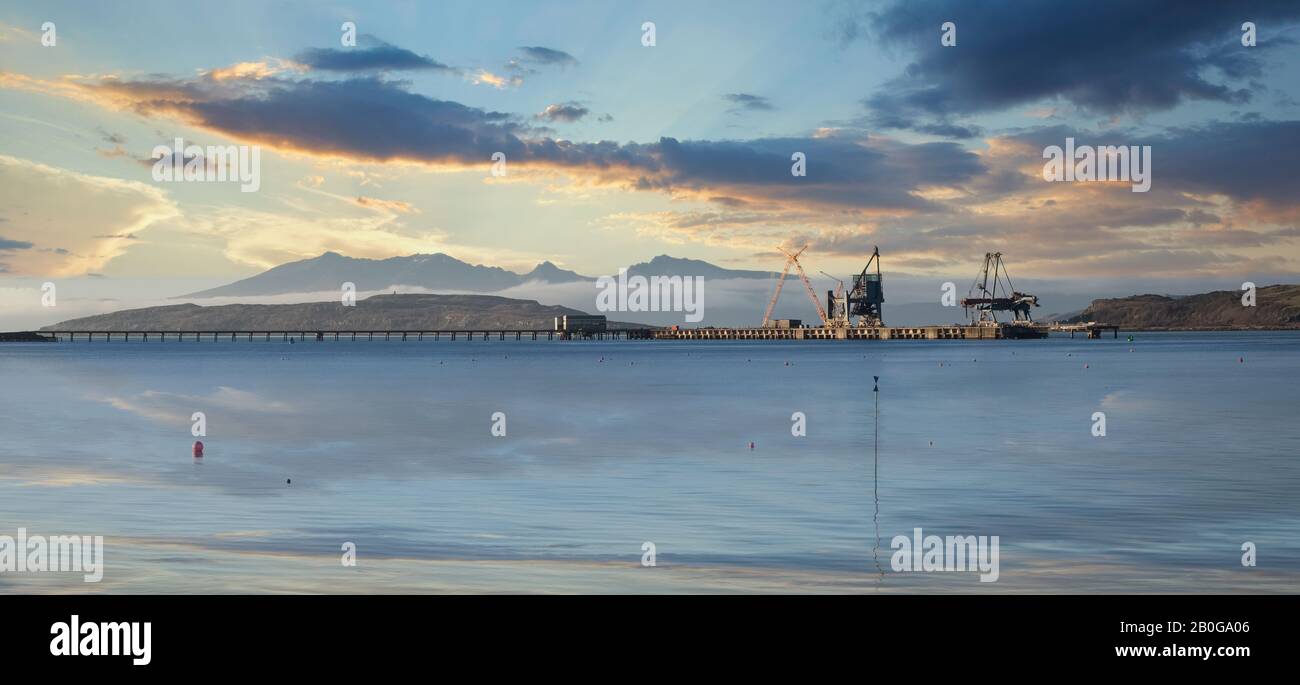 The Isle of Arran with the Iron Oar Terminal Jetty in front as the sun was rising in front of Arran causing reflective light on the jetty. Stock Photo