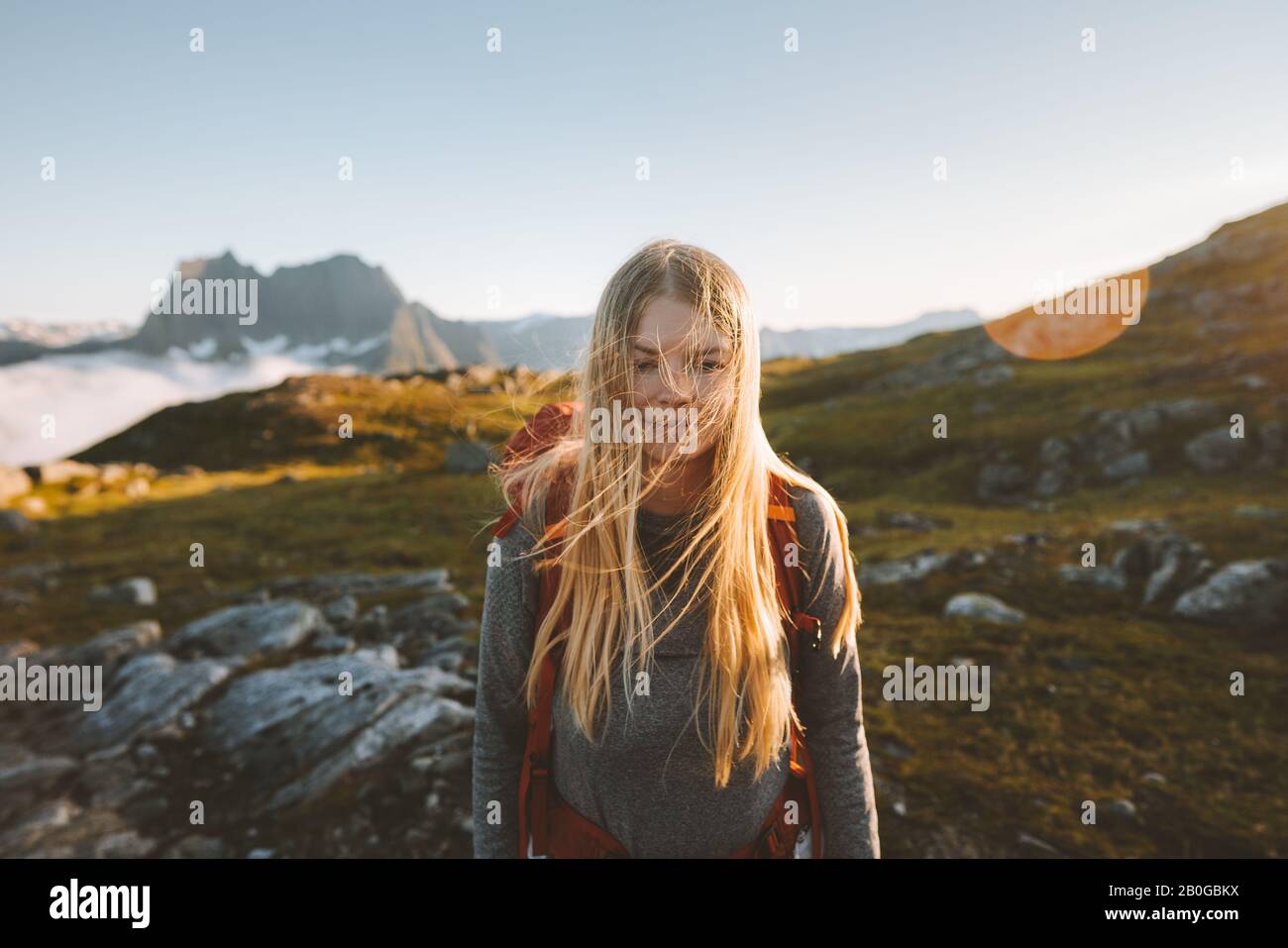 Woman hiking in mountains travel adventure healthy lifestyle blonde hair girl active summer vacations backpacking in Norway Stock Photo