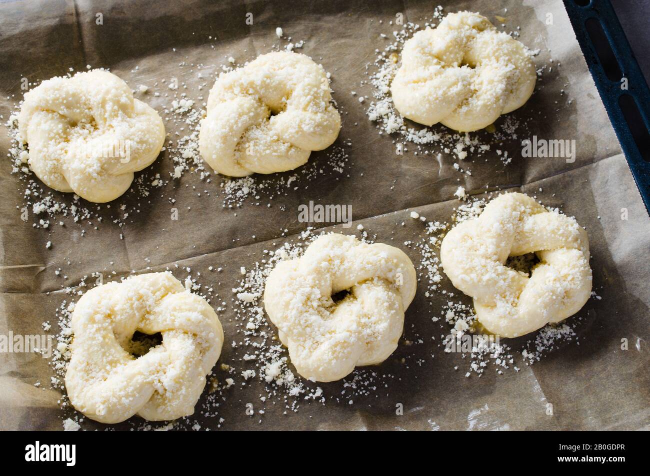 Preparation process - raw unbaked buns. Ready to bake homemade traditional buns on baking paper. Rustic style. Traditional pastry Stock Photo