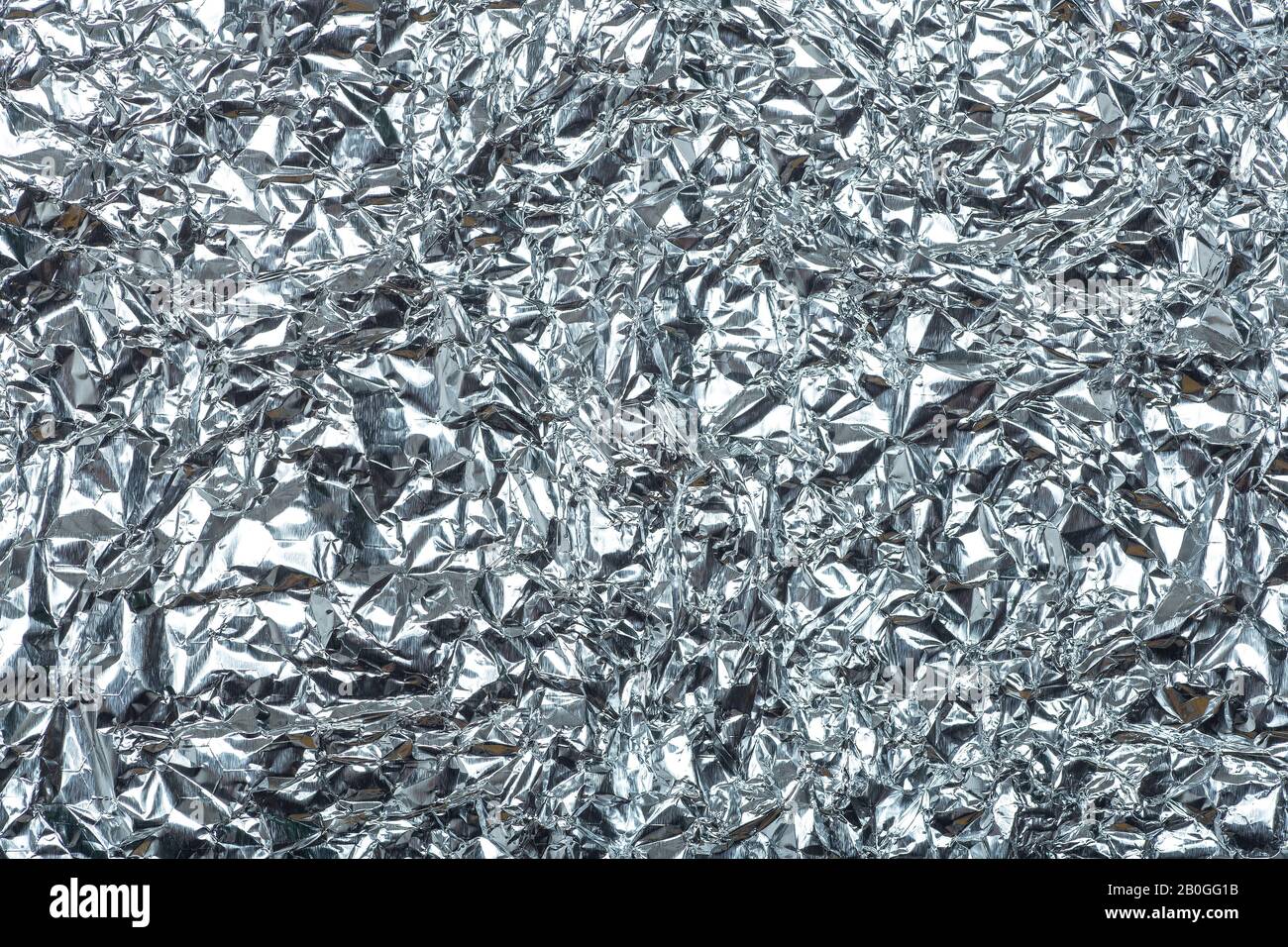 Crumpled foil background. The texture of crumpled iron aluminum foil reflective color. Copy space. Stock Photo