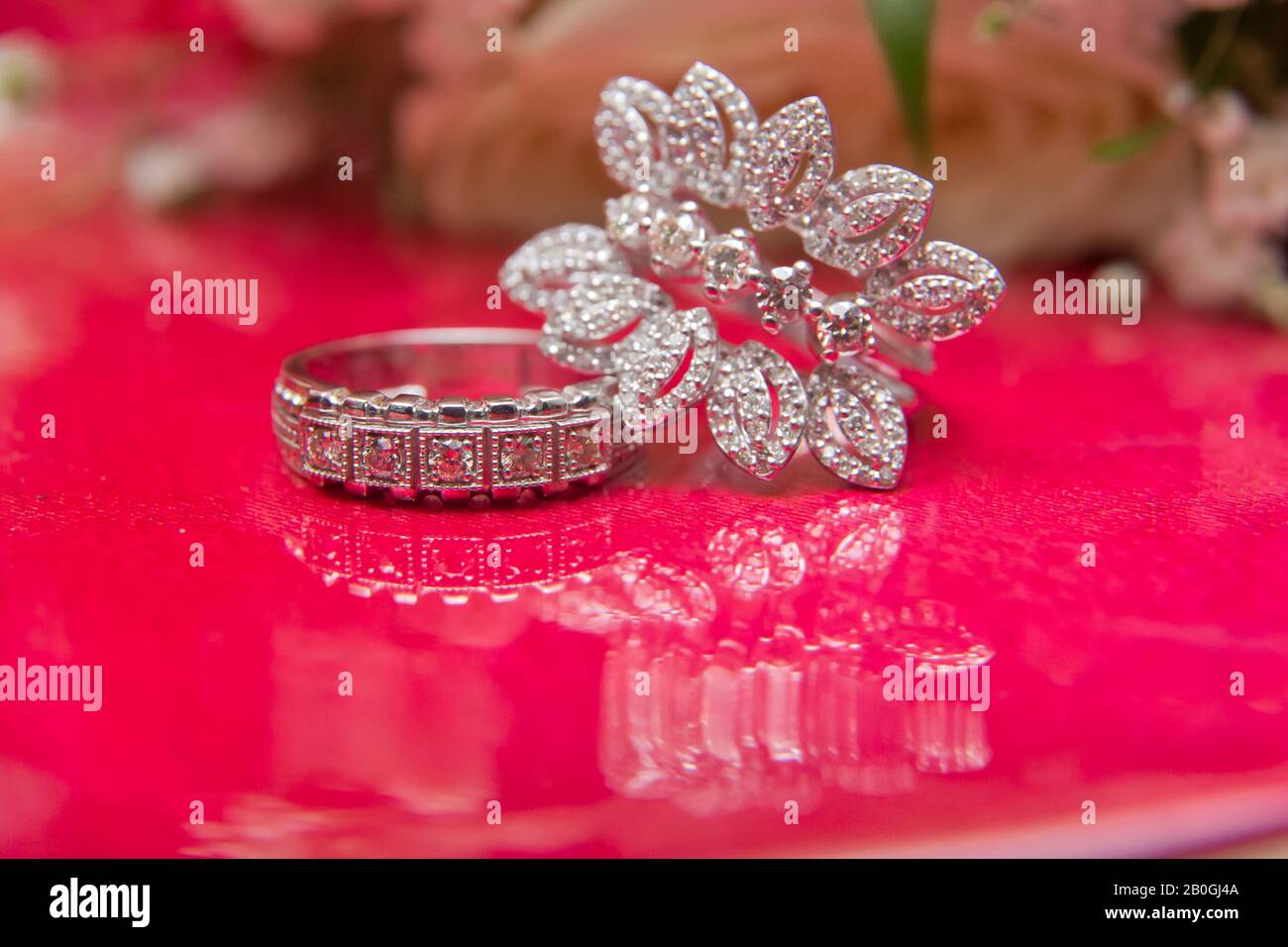 White wedding rings . flower bouquet selective focuse .Two silver wedding rings red background . Romantic and lovely wedding , macro . Bride and groom Stock Photo
