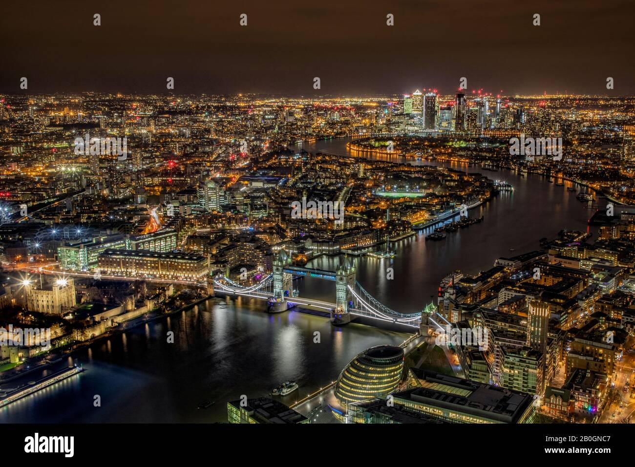 Aerial view of Tower Bridge and London after dark showing canary wharf and the city along the Thames Stock Photo