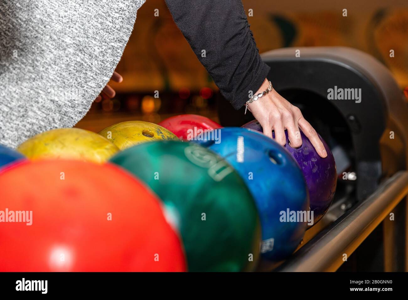 Hand picking up bowling ball at bowling alley. Stock Photo