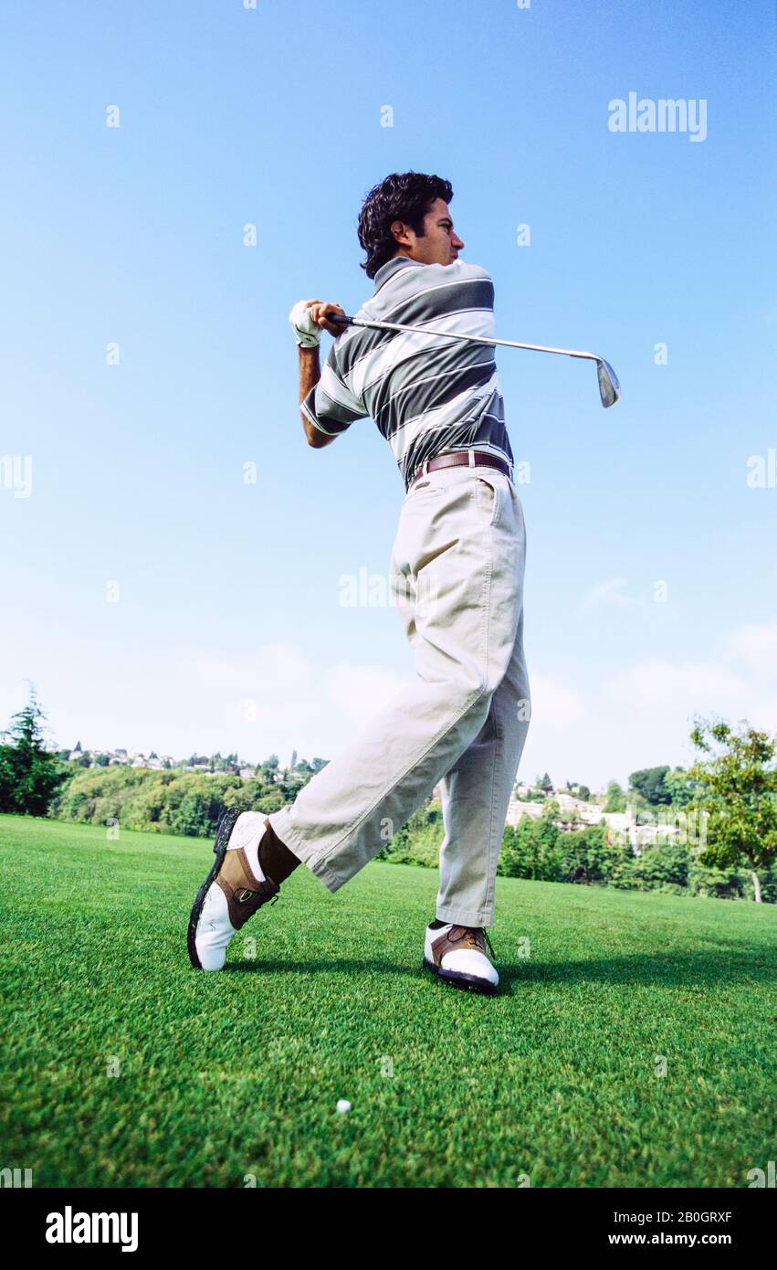 Early 30's Caucasian man watching his golf ball on the follow through of a tee shot. Stock Photo