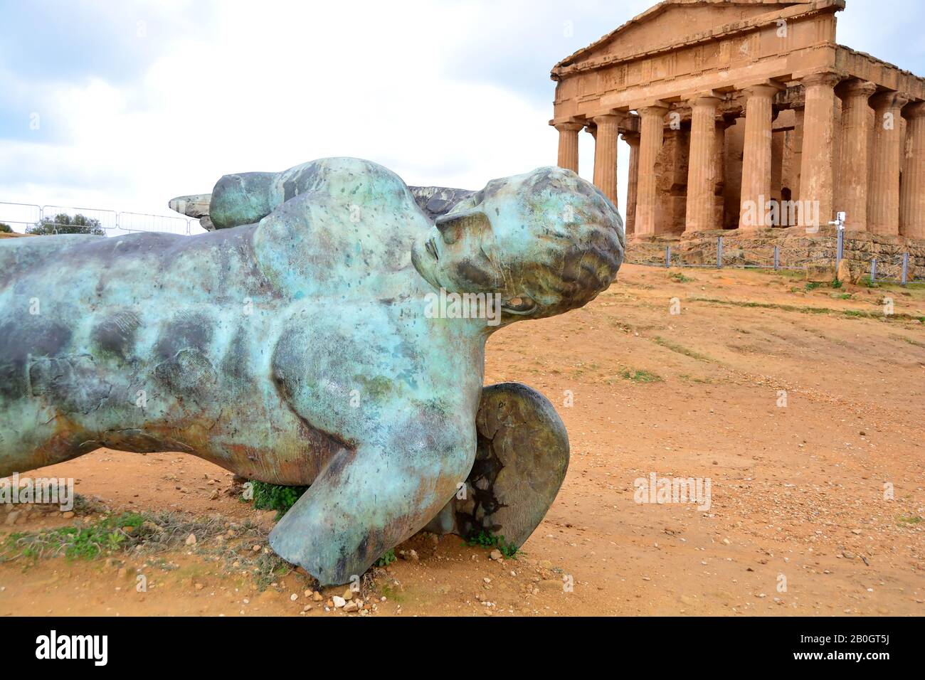 Statue of fallen Icarus in bronze in front of the 2,400 year old Temple of Concordia, one of the best preserved Ancient Greek Temples at Agrigento, Th Stock Photo