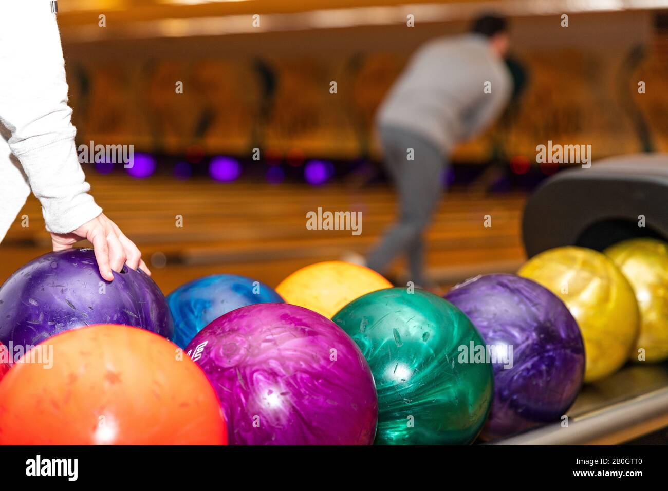 Hand picking up bowling ball at bowling alley. Stock Photo