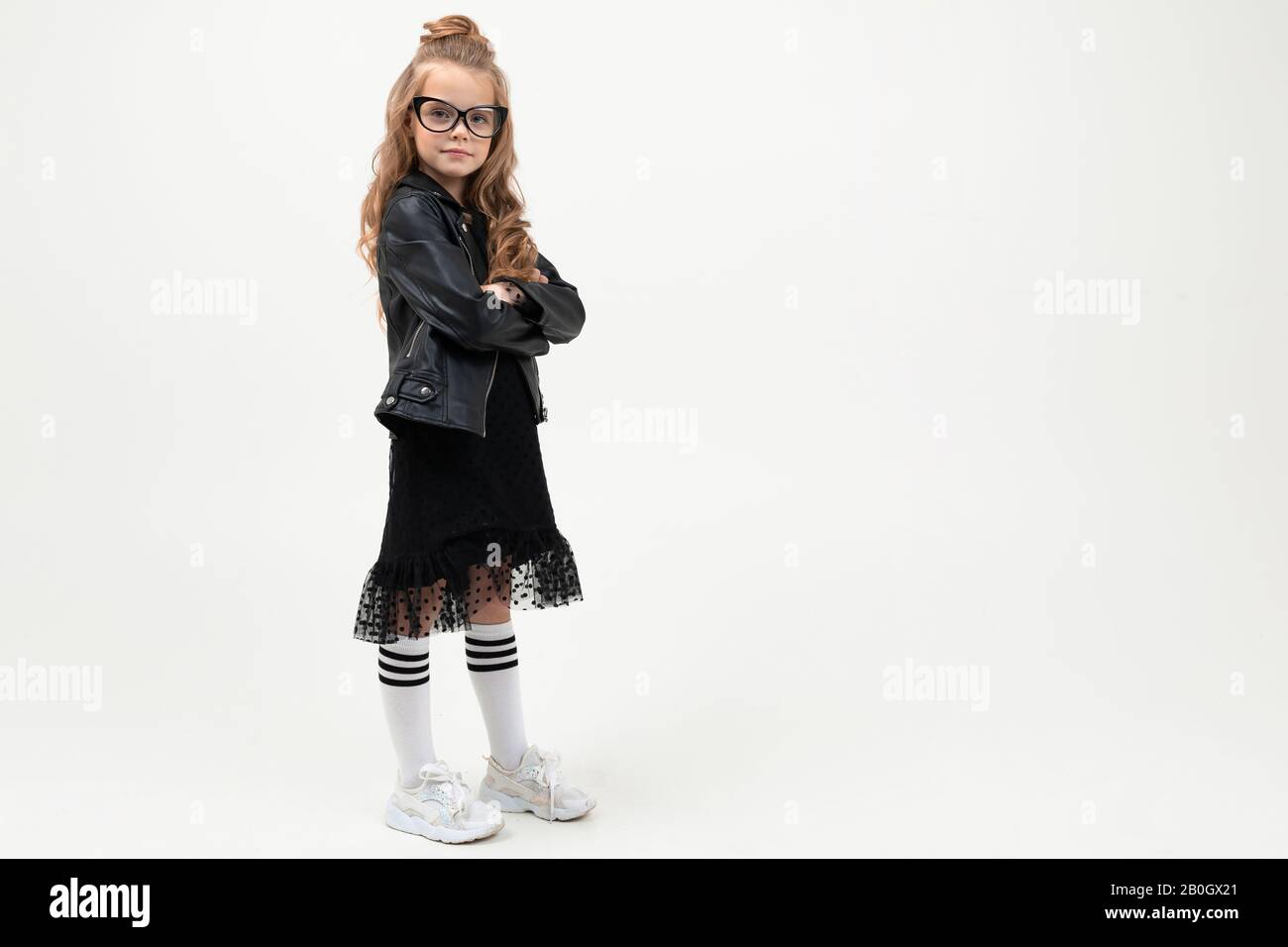 Pretty little girl in black dress stands isolated on white background ...