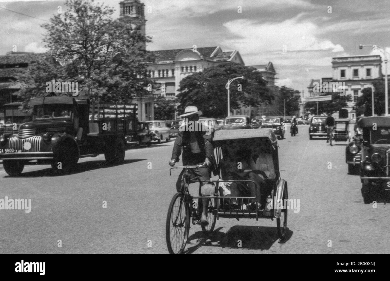 Singapore. 1958. Street scene with cars, a lorry and a trishaw Stock
