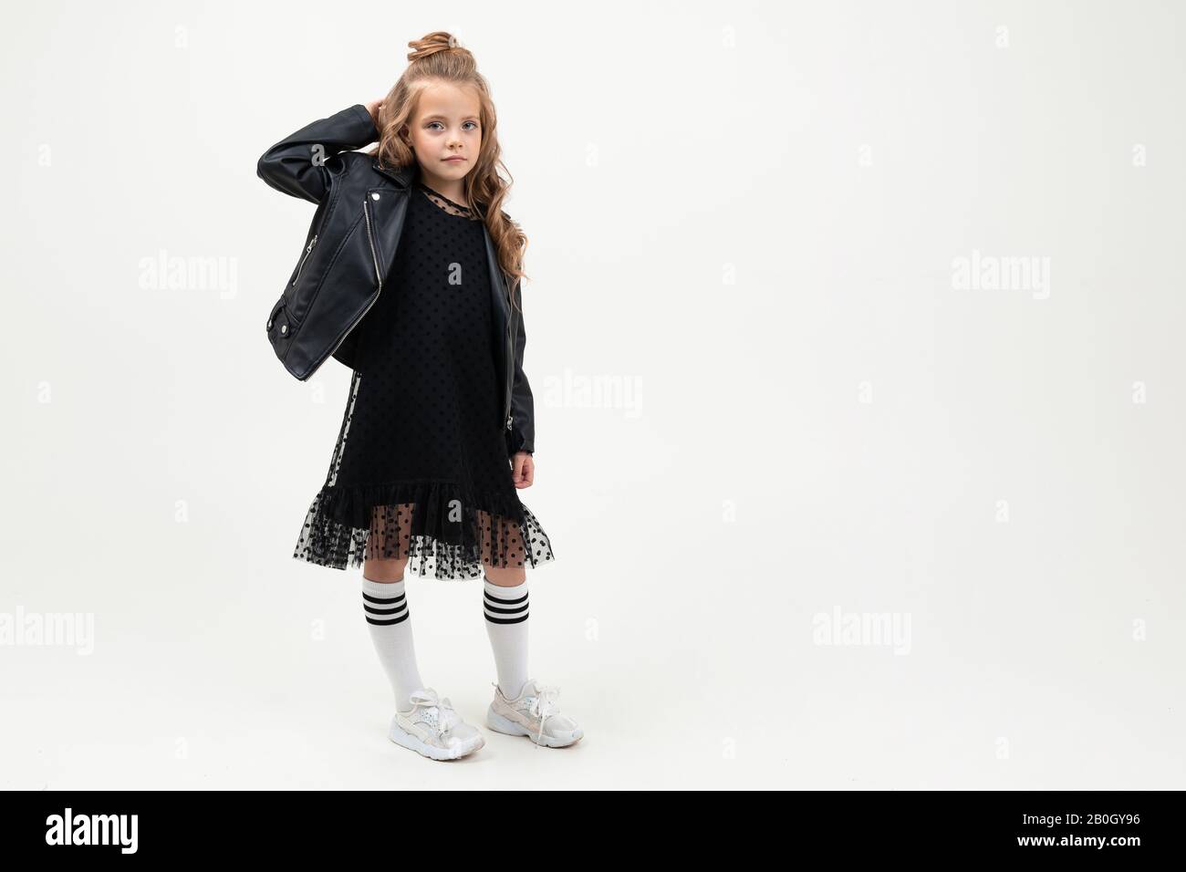 Pretty little girl in black dress stands isolated on white background ...
