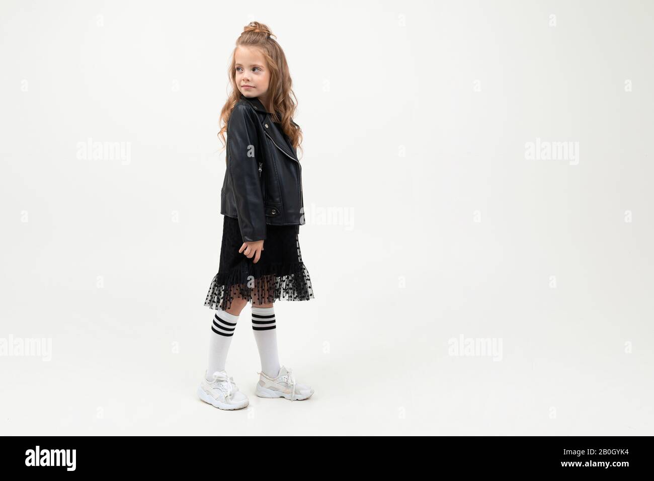 Pretty little girl in black dress stands isolated on white background ...