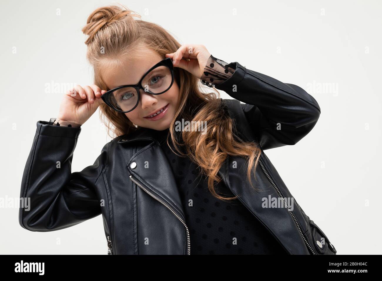 Pretty little girl in black dress stands isolated on white background ...