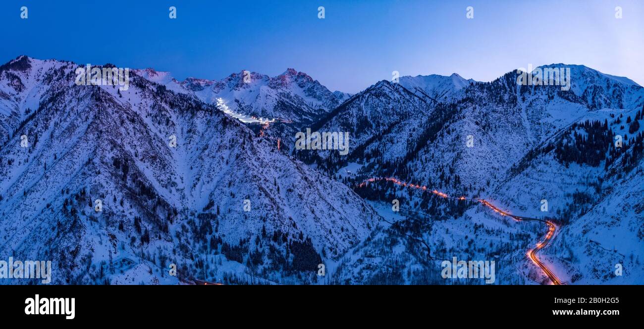 Panorama of the mountains with the road to the ski resort of Chimbulak. Late winter evening Stock Photo