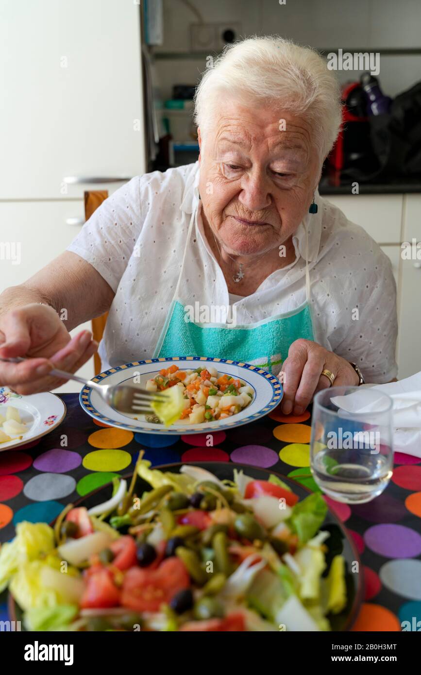 Old woman eating healthy food alone at home Stock Photo
