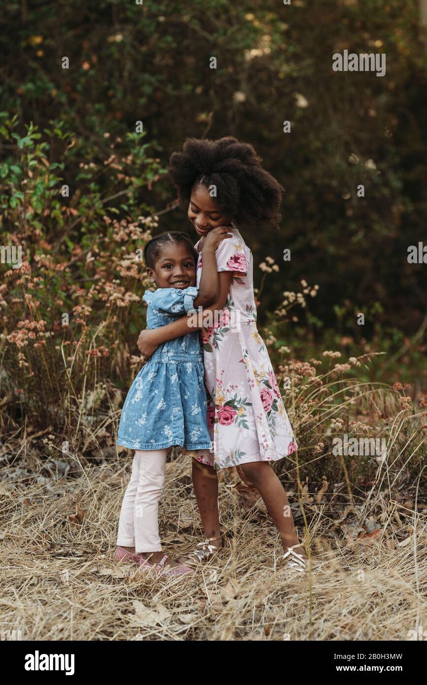 Portrait of two sisters hugging in backlit field Stock Photo - Alamy