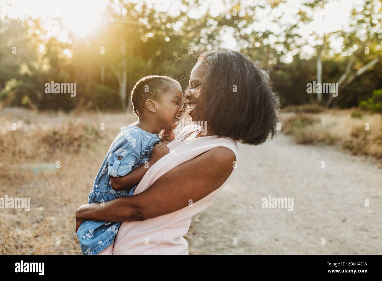 Close up of happy grandmother holding young granddaughter in sun Stock Photo