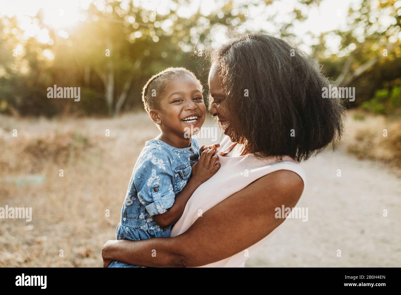 Close up of happy grandmother holding smiling granddaughter outside Stock Photo