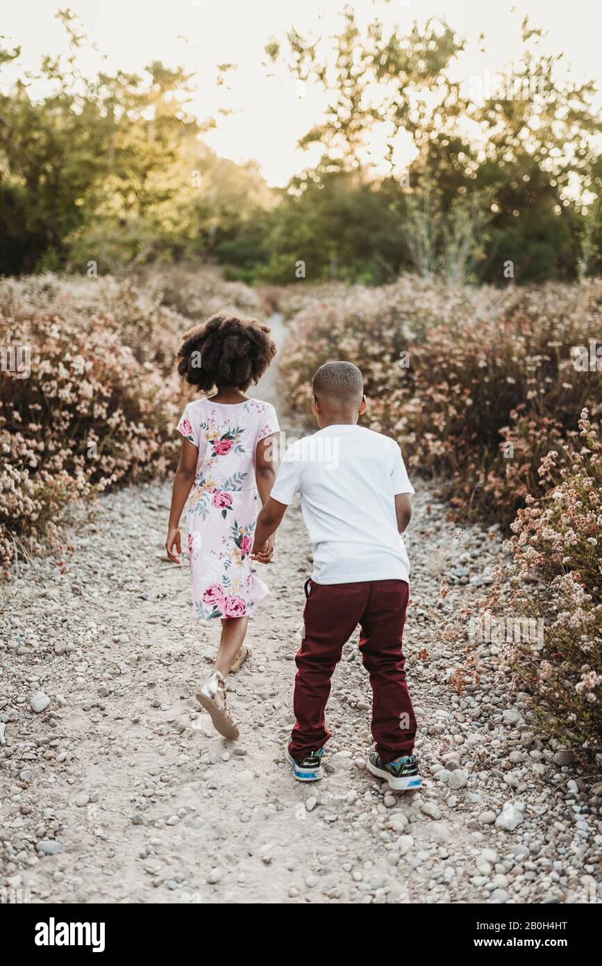 Close up of brother and sister running away holding hands Stock Photo