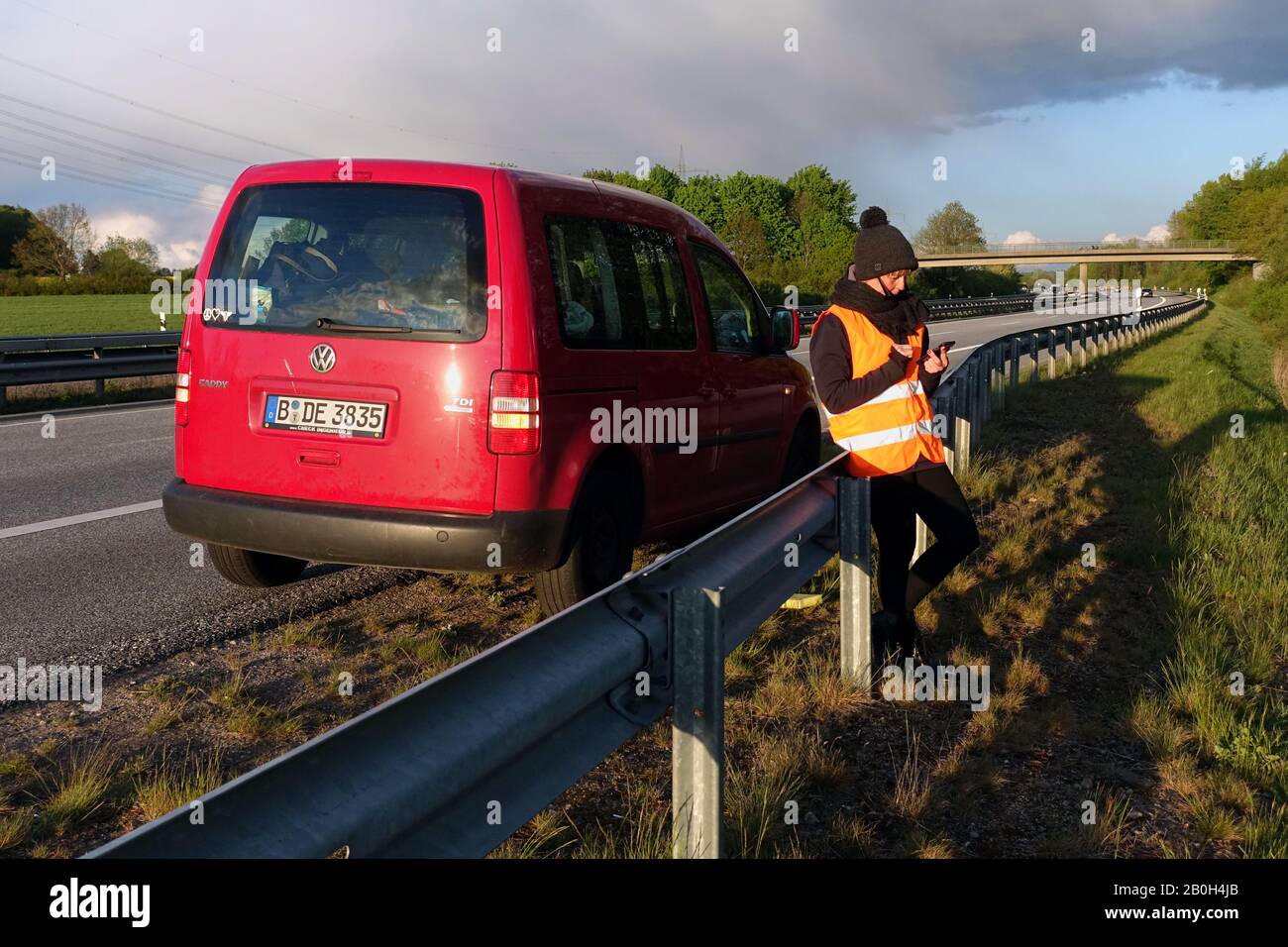 04.05.2019, Hamburg, Hamburg, Germany - Woman standing behind the crash barrier in a car breakdown on the A24 and looking at her mobile phone. 00S1905 Stock Photo