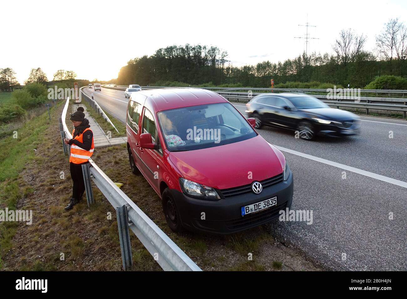 04.05.2019, Hamburg, Hamburg, Germany - Woman standing behind the crash barrier in a car breakdown on the A24 and looking at her mobile phone. 00S1905 Stock Photo