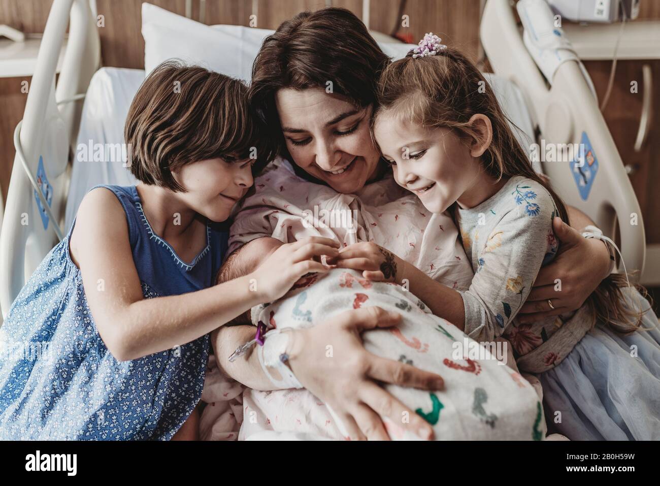 Mid view of mom and daughters holding newborn son Stock Photo