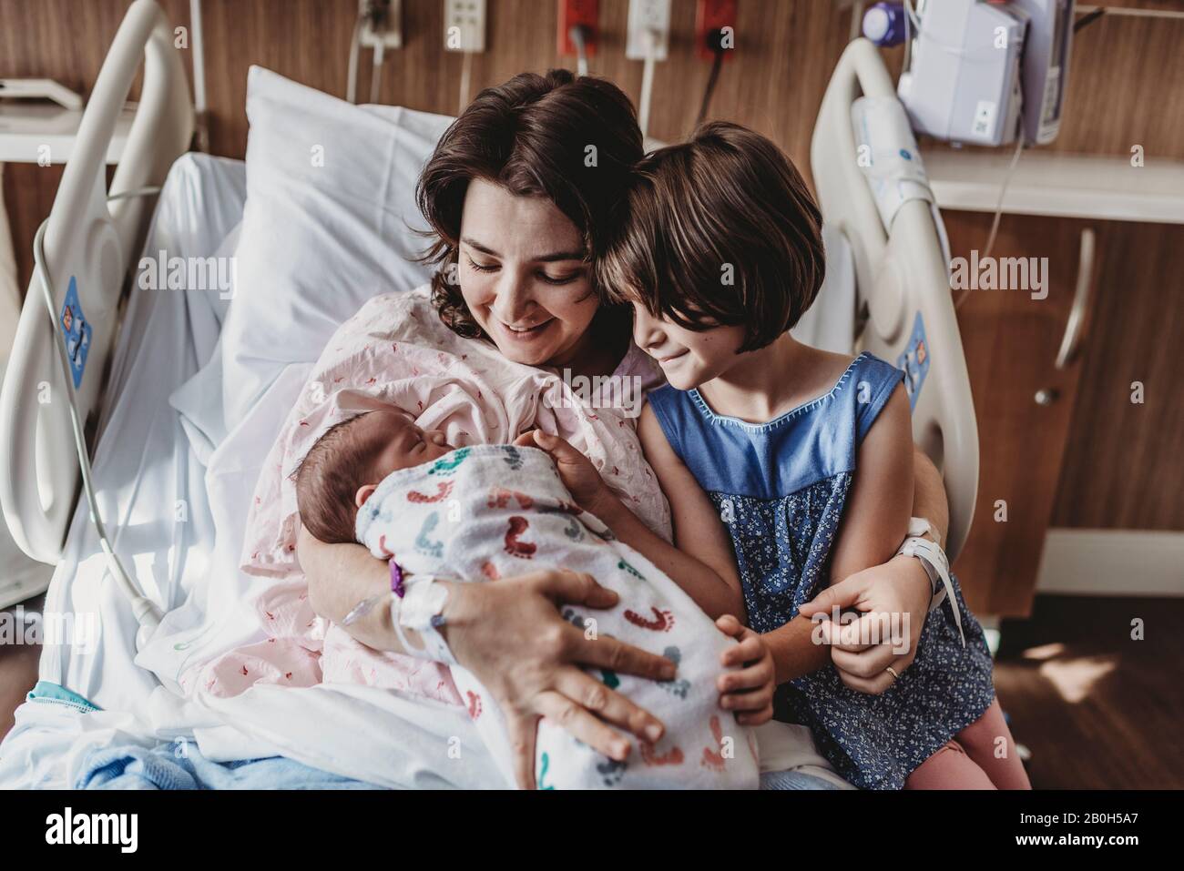 Mid view of mother holding newborn son meeting siblings Stock Photo