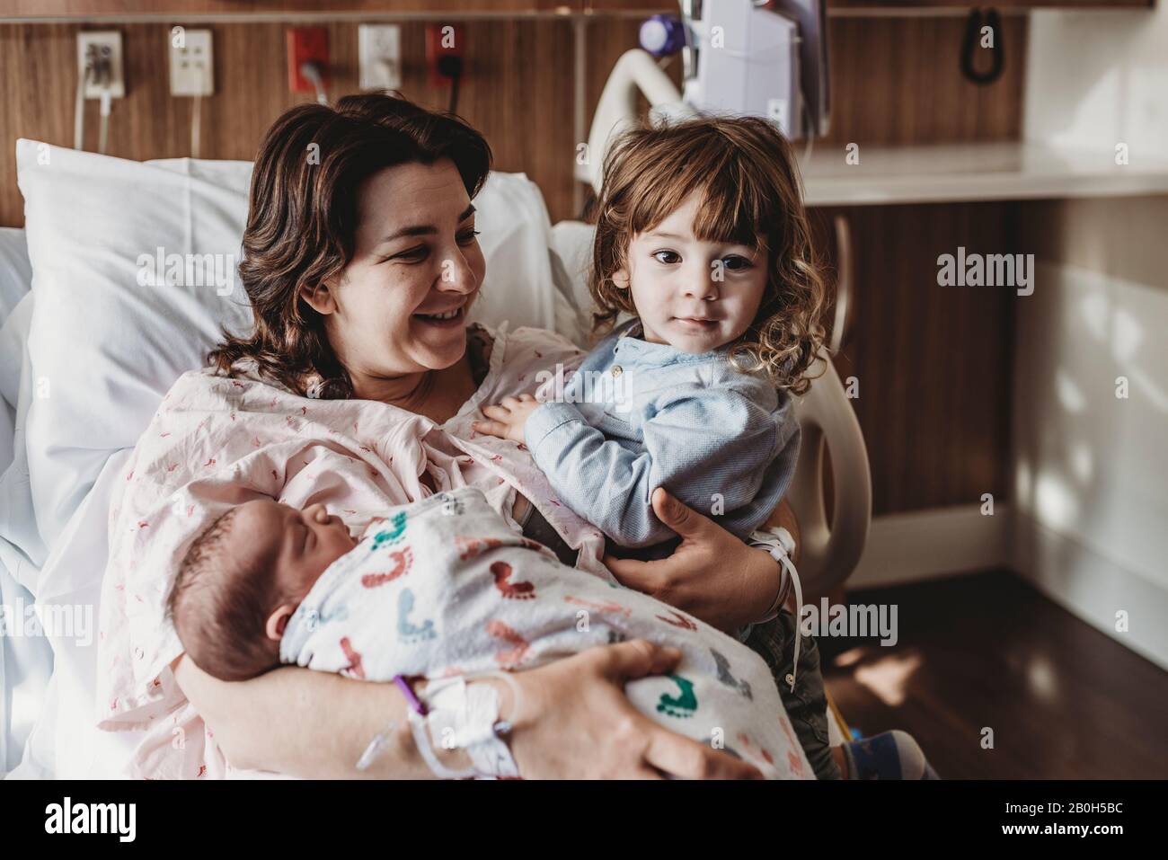 Mid view of mother holding newborn son meeting siblings Stock Photo